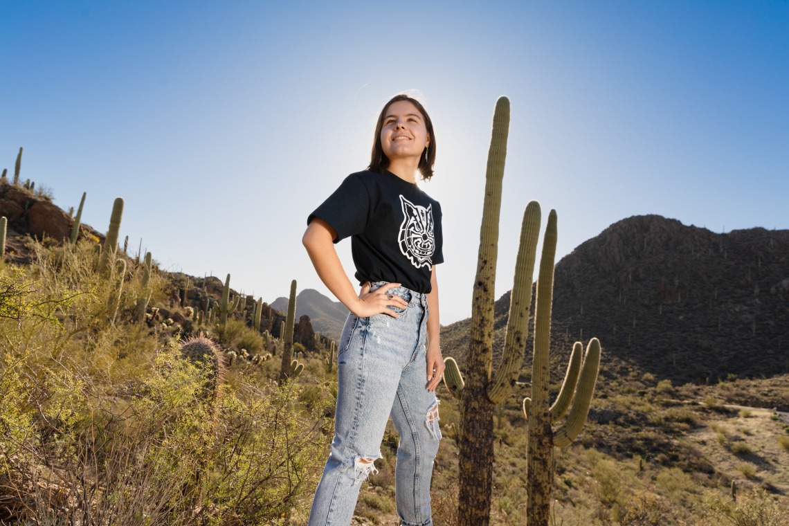 Student with blue Native Wildcat t-shirt on, standing in the desert